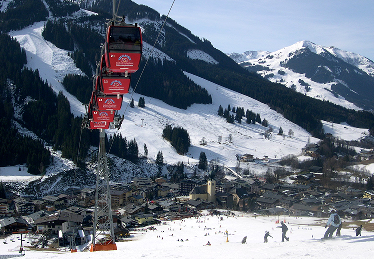 Skipiste mit Bergdorf im Hintergrund